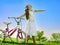 Child girl wearing white skirt rides bicycle into park.