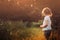 Child girl in white shirt on the walk on summer sunset field