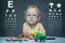 Child with glasses sits at a table on the background of the table for an eye examination