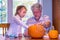 Child and grandfather carve a pumpkin