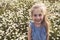 Child on green daisy grass in a summer park sunset time