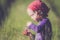 Child in green wild meadow eating wild strawberries. Summer happy times.