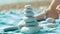 Child hand building pebbles tower on seaside. Pile of balanced round stones