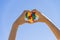 Child hand holding colorful heart on blue sky background. World autism awareness day concept