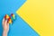 Child hand holding colorful heart on yellow and blue background. World autism awareness day concept