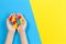 Child hand holding colorful heart on yellow and blue background. World autism awareness day concept