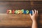 Child hand holding number zero with sets of other colorful numbers plastic toy on a wooden table