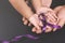 Child hand holding Purple ribbon on adult caring hand against black background.