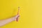 Child hand holding toothbrush pink color on yellow background. Mockup with copy space. Dental hygiene and healthy concept