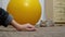Child Hand Playing on Carpet with Curious Gray Cat near Big Yellow Fitness Ball
