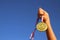 Child hand raised, holding gold medal against sky. education, success, achievement, award and victory concept.