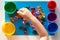 Child hand separating by color multicolored toy stones scattered on the blue surface into colorful cups