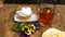 Child hand takes with teaspoon tasty fresh cake on saucer, on wooden table. On table there is also cup with tea, pansy