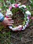 Child hand touches a wreath of white and pink daisies lying on a haystack next to freshly picked long grass