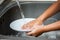 Child hand washing dishes over the sink