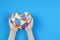 Child hands holding colorful polygonal paper origami heart on light blue paper background. World autism awareness day