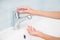 Child hands pushing bathroom mixer with flowing clean water for