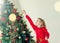 The child hangs a garland on the Christmas tree. Christmas morning