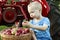 Child having fun apple picking and sitting on a red antique tractor