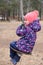 Child having  fun outdoors swinging on wooden homemade swing tied to a tree with a rope in spring or autumn