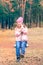 Child having  fun outdoors swinging on wooden homemade swing tied to a tree with a rope in spring or autumn