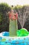 Child having fun playing in water in a garden paddling pool the boy is happy and smiling