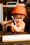 Child with helmet in orange hard hat. Tools construction. Boy hammering. Kid hammers nail.