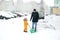 Child helps his father to remove snow in the yard of the house