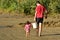 Child helps to carry a heavy bucket