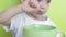 The child himself eats food with a spoon from a plate, sitting at a table. Close-up