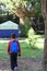 Child on his back with a blue backpack. The boy is heading for a tent with a walkie talkie in his hand