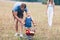 Child with his parents pushing a whellbarrow outdoors