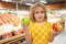 Child hold apple fruits at grocery store. Kid in a food store or a supermarket. Little kid going shopping. Healthy food