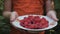 Child hold out a plate full of ripe garden raspberries