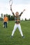 Child holding badminton racquet and triumphing while sibling standing behind