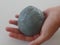 Child holding a ball of grey green slime in the palm of her hand