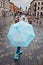 Child holding big blue umbrella walking in a downtown on rainy gloomy autumn day