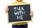 Child holding blackboard with text saying Talk With Me.