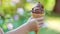 Child holding chocolate ice cream in waffle cone in green park, summer sweetness