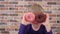 Child holding a donuts in two eyes like glasses and having fun.