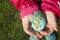 Child holding an egg with Planet Earth painted on it on a sunny