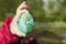 Child holding an egg with Planet Earth painted on it on a sunny