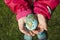 Child holding an egg with Planet Earth painted on it on a sunny day outdoors