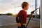 Child holding the hose of a fuel pump at sunset at a gas station