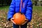 Child holding pumpkin with spider on fall leaves, halloween