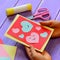 Child is holding a Valentines day greeting card in his hands. Small child is showing a Valentines day greeting card