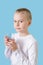 Child holds glass of water in his hands. Blond little boy with water glass, looking at the camera