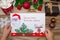 A child holds a letter to Santa Claus at the North Pole in Lapland, children`s hands on a wooden background with decorations and C