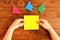 Child holds a paper square in his hands. Child making origami fish. Set of origami fish on a wooden table