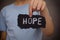 Child holds piece of black paper with word Hope